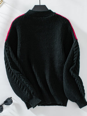 Black cable knit sweater with contrast pink shoulder detail and mock neck.