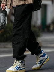 Men's black drawstring sweatpants with pockets, styled with high-top sneakers.