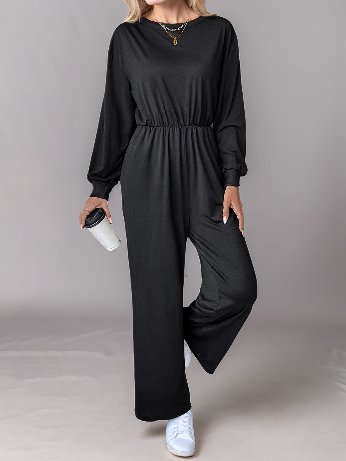 Black wide leg jumpsuit with long sleeves, crew neck, and elasticated back-tie waist.