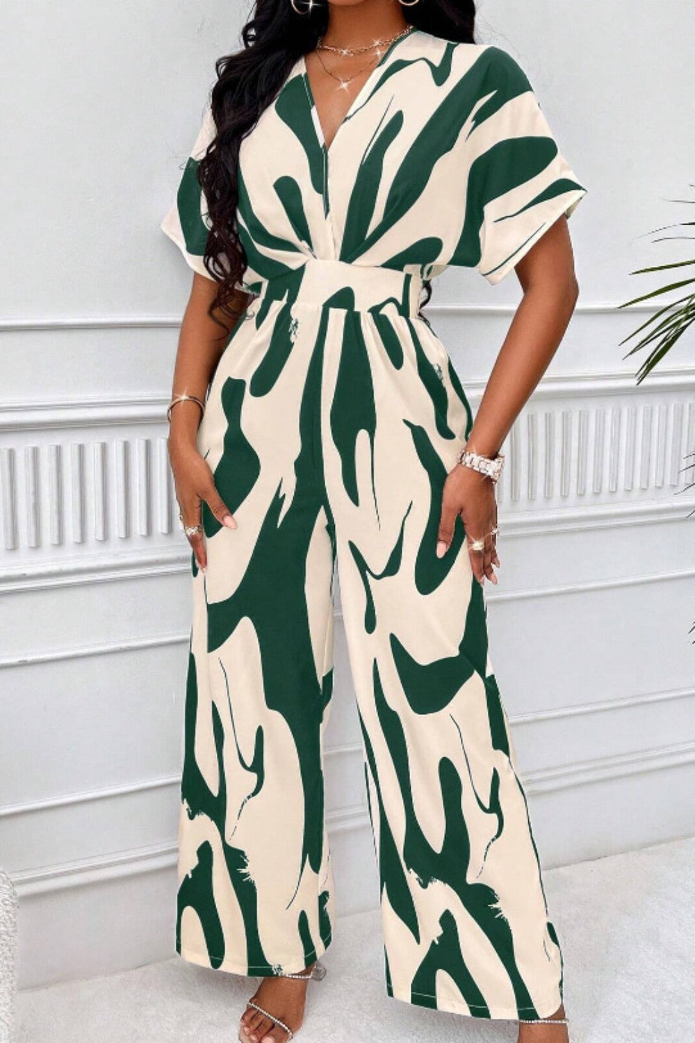 Dark green and cream abstract brushstroke wide-leg jumpsuit with short sleeves and a V-neck.
