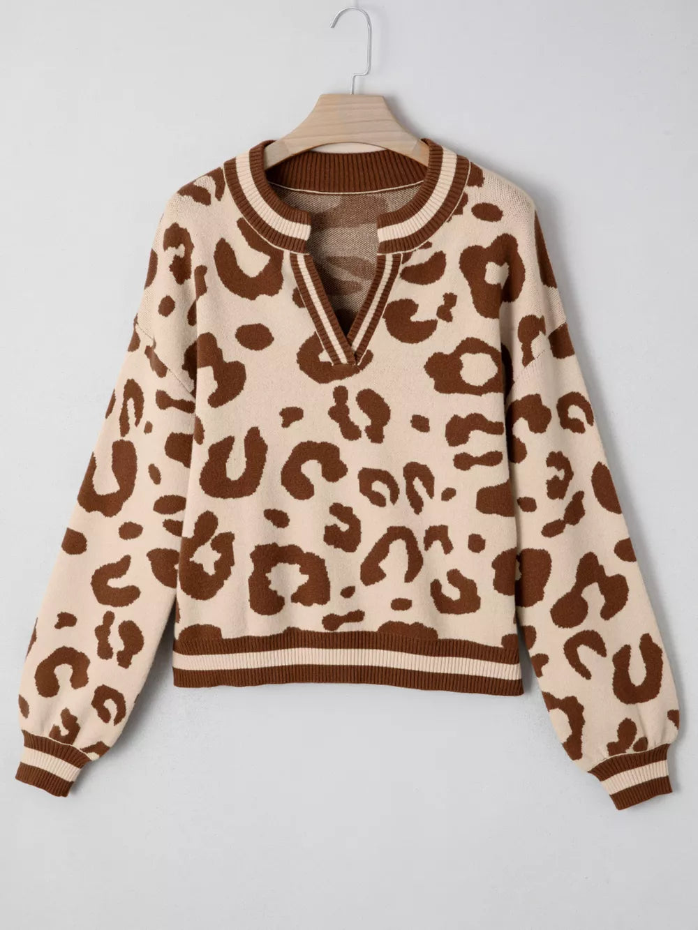 Chic leopard print knit sweater with notched neckline and striped trim.