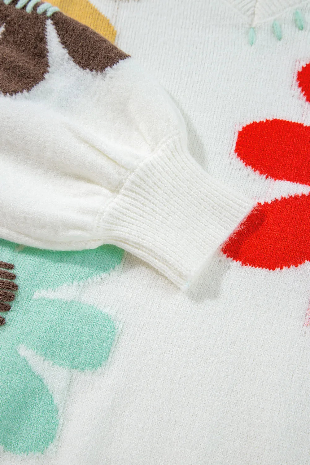 White knit sweater with embroidered floral pattern and ribbed cuffs.