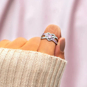 Silver ring with intertwined heart design and pink zirconia stones.