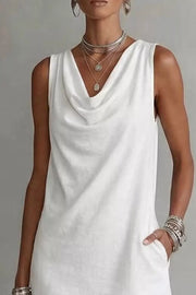 White cowl neck mini dress with pockets and layered necklaces.