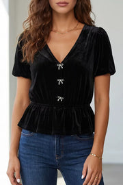 Black velvet peplum shirt with V-neck, short puff sleeves, and bow button front.
