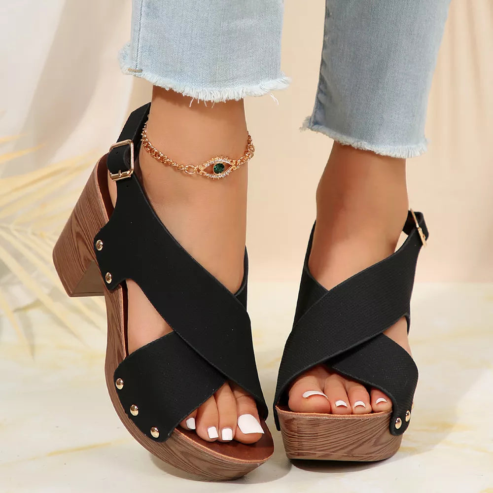 Black crisscross high heel sandals with wood-look block heel and stud details.