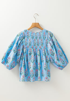 Sky blue floral print smocked yoke blouse with puff sleeves and vertical stripes.