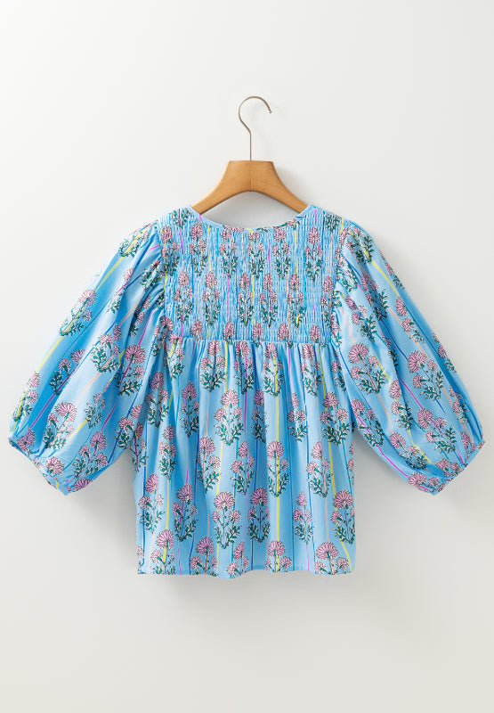 Sky blue floral print smocked yoke blouse with puff sleeves and vertical stripes.