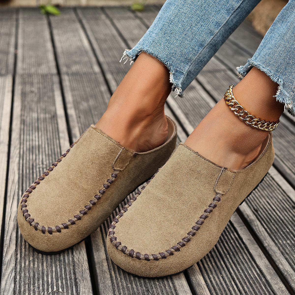 Comfortable beige suede slip-on flats with decorative stitching and a gold chain anklet.