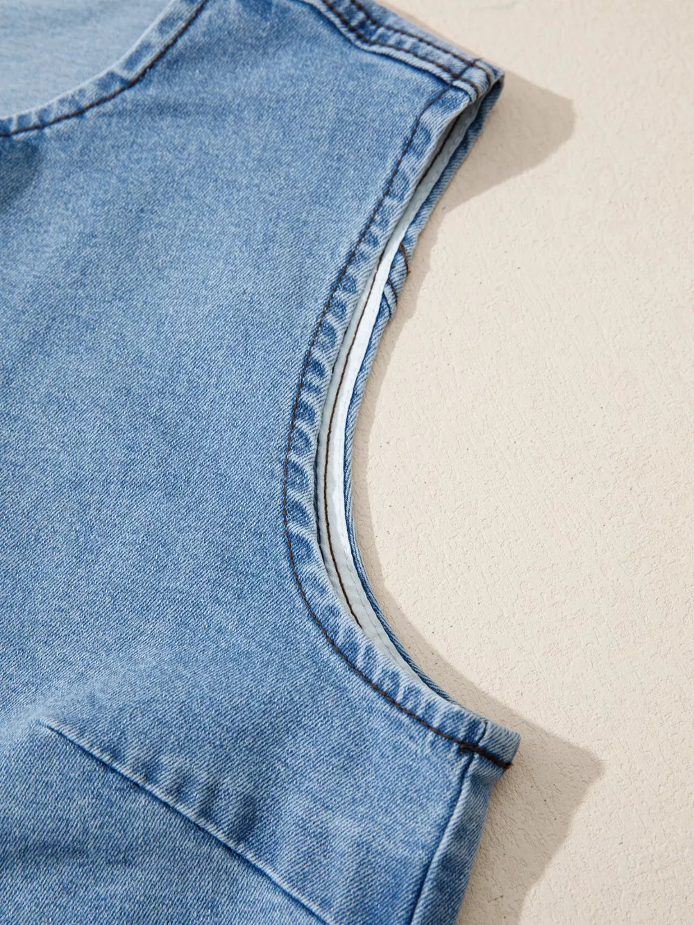 Denim vest with contrast trim detail on armhole, light wash cotton.