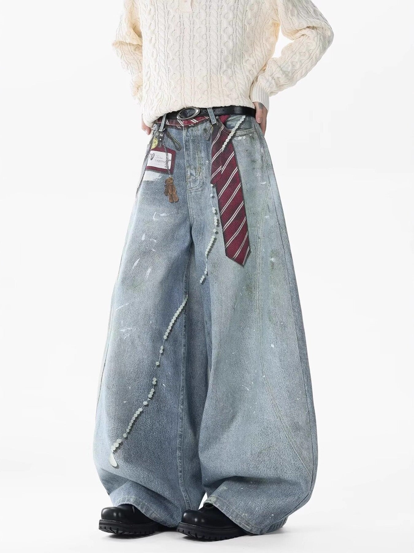 Oversized light wash denim jeans with pearl accents, paint splatters, and a tie detail.