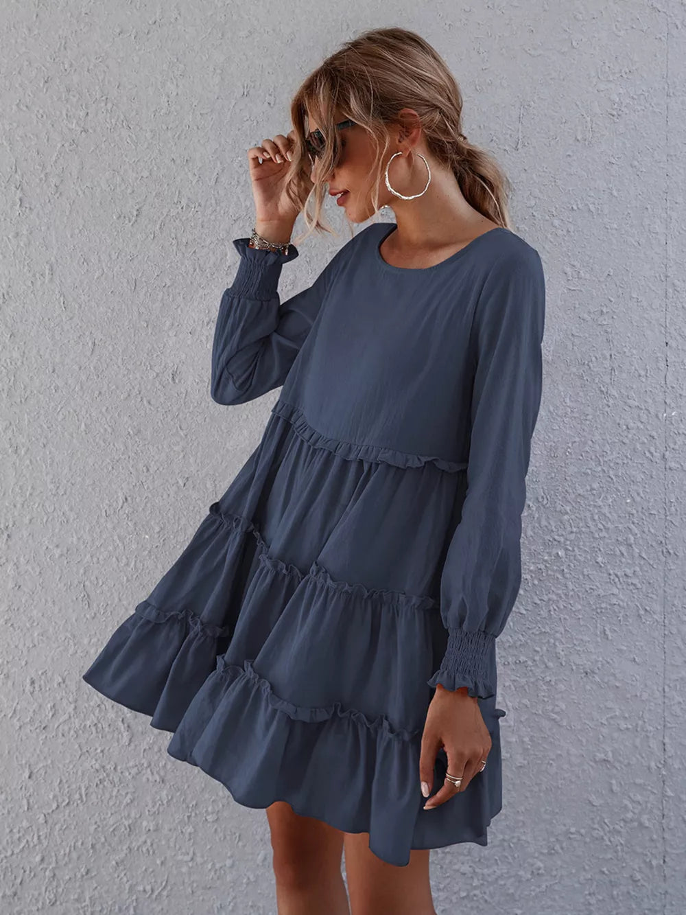 Navy blue tiered mini dress with long sleeves and ruffled details.