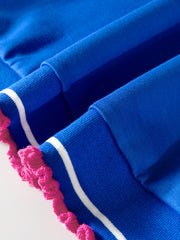 Blue polo shirt with white stripes and pink frill trim on the cuffs.