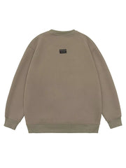Oversized khaki cotton crew-neck sweatshirt with a small black logo patch on the back.