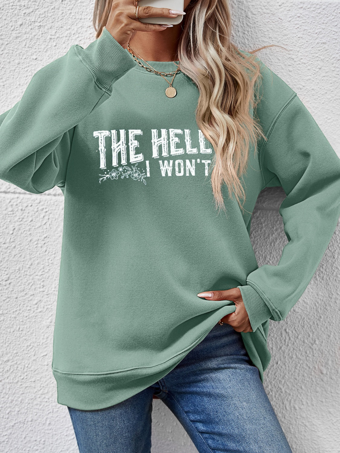 Sage green crewneck sweatshirt with white graphic text and floral detail.