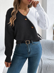 Asymmetrical black and white colorblock knit sweater with button detail and V-neck.