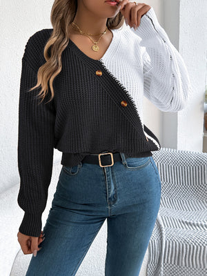 Asymmetrical black and white colorblock knit sweater with button detail and V-neck.