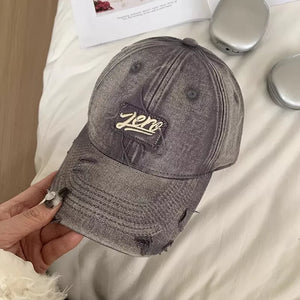 Distressed dark gray cotton baseball cap with embroidered "Zero" patch and frayed details.