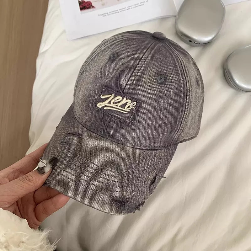 Distressed dark gray cotton baseball cap with embroidered "Zero" patch and frayed details.