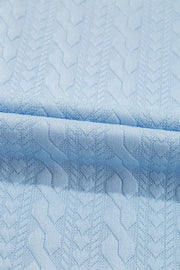 Light blue cable knit loungewear set fabric detail with textured chevron pattern.