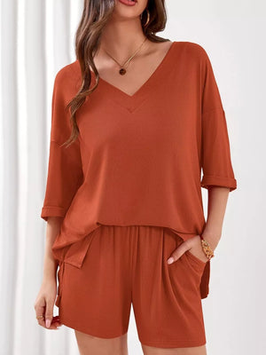 Orange-red V-neck loungewear set with cuffed sleeves and drawstring shorts with pockets.