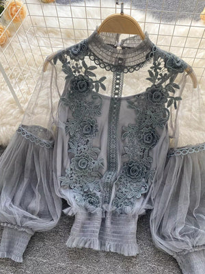 Gray lace blouse with floral embroidery, sheer puff sleeves, and ruffled cuffs.