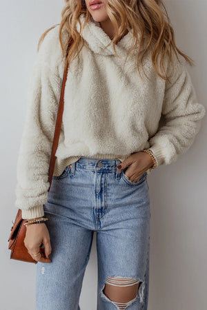 Beige plush fleece cropped hoodie with ribbed cuffs and neckline, styled with jeans.