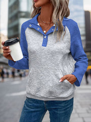 Blue and gray quilted raglan henley sweatshirt with button detail and front pocket.