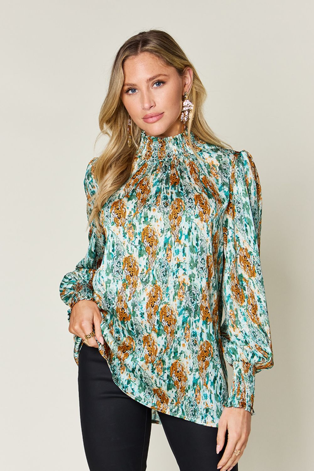 High neck abstract print blouse in green with smocked neckline and cuffs.