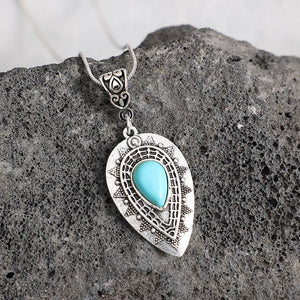 Silver teardrop pendant necklace with turquoise inlay and boho detailing.