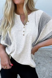 Colorblock waffle knit henley top in gray with button detail and textured sleeves.