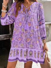 Purple floral mini dress with tassel tie neckline and tiered hem.