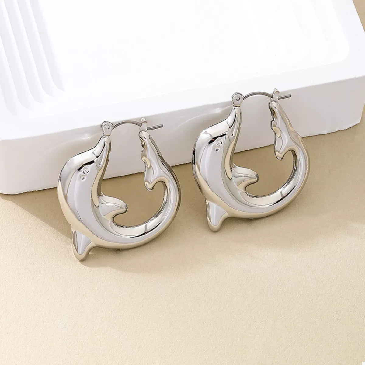 Silver dolphin hoop earrings with a polished finish.