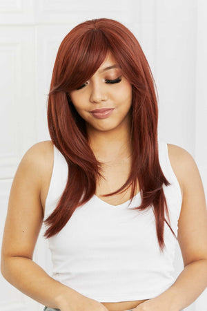 Layered copper red synthetic wig with chic bangs styled on a woman wearing a white tank top.