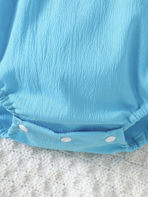 Pastel blue cotton baby romper with textured fabric and white snap closure.