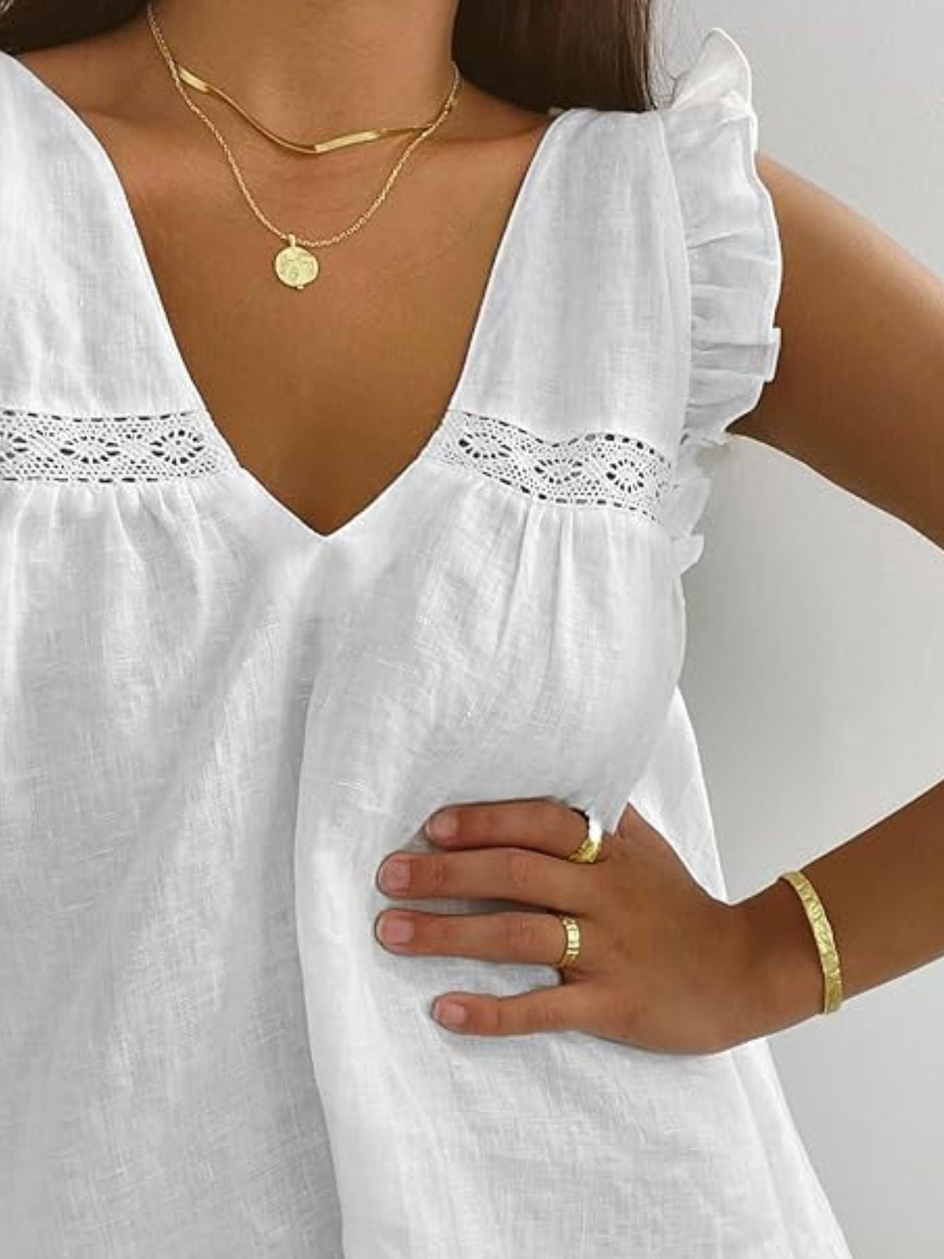 White ruffled V-neck top with lace trim and flutter sleeves.