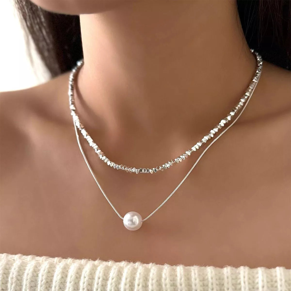 Elegant double layered silver necklace with a single pearl accent.