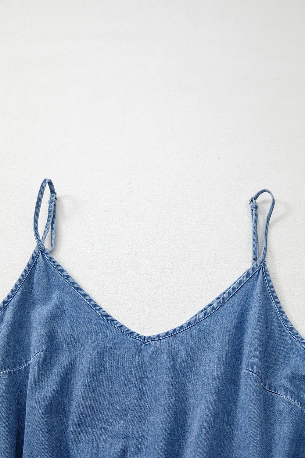 Medium wash denim romper with spaghetti straps and v-neckline