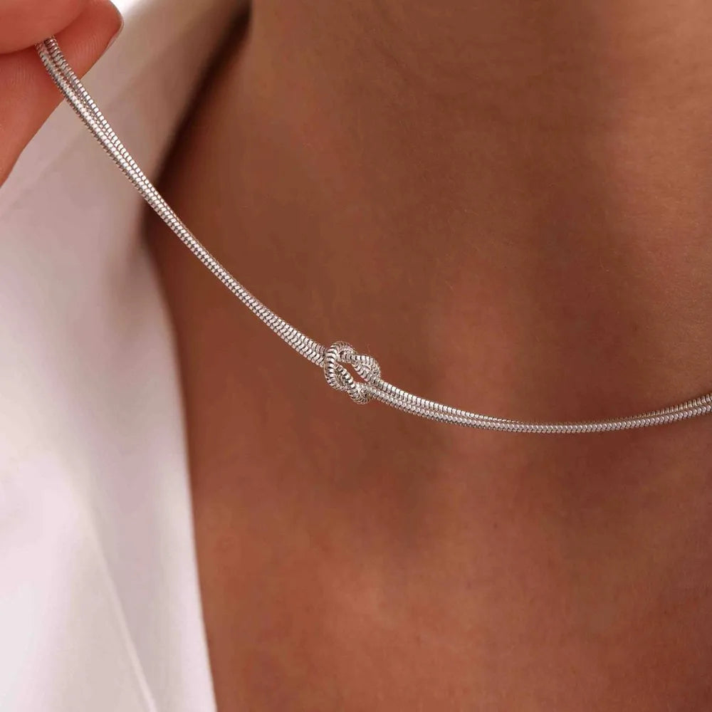 Silver serpent knot necklace with a snake chain detail.