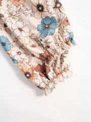 Floral tiered hem dress with ruffled cuffs in cream with blue, brown, and peach flowers.