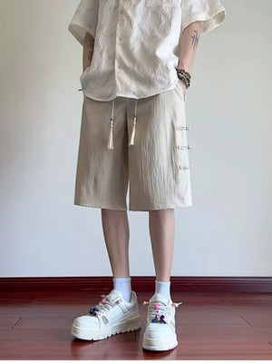 Beige chino shorts with drawstring and decorative side closures, relaxed fit.