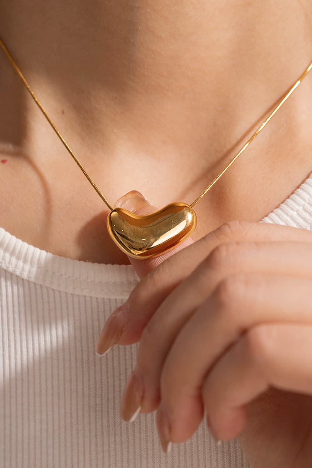 Gold bean-shaped sculptural pendant necklace on a thin chain.