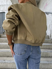Olive bomber jacket with sculpted sleeves and ribbed cuffs, styled with jeans.