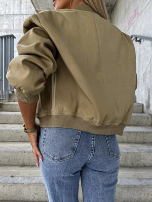 Olive bomber jacket with sculpted sleeves and ribbed cuffs, styled with jeans.