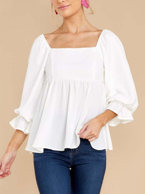 White babydoll blouse with square neckline, puff sleeves, and ruffled cuffs.