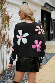 Black acrylic sweater with colorful daisy motif, drop shoulder, and crew neck.