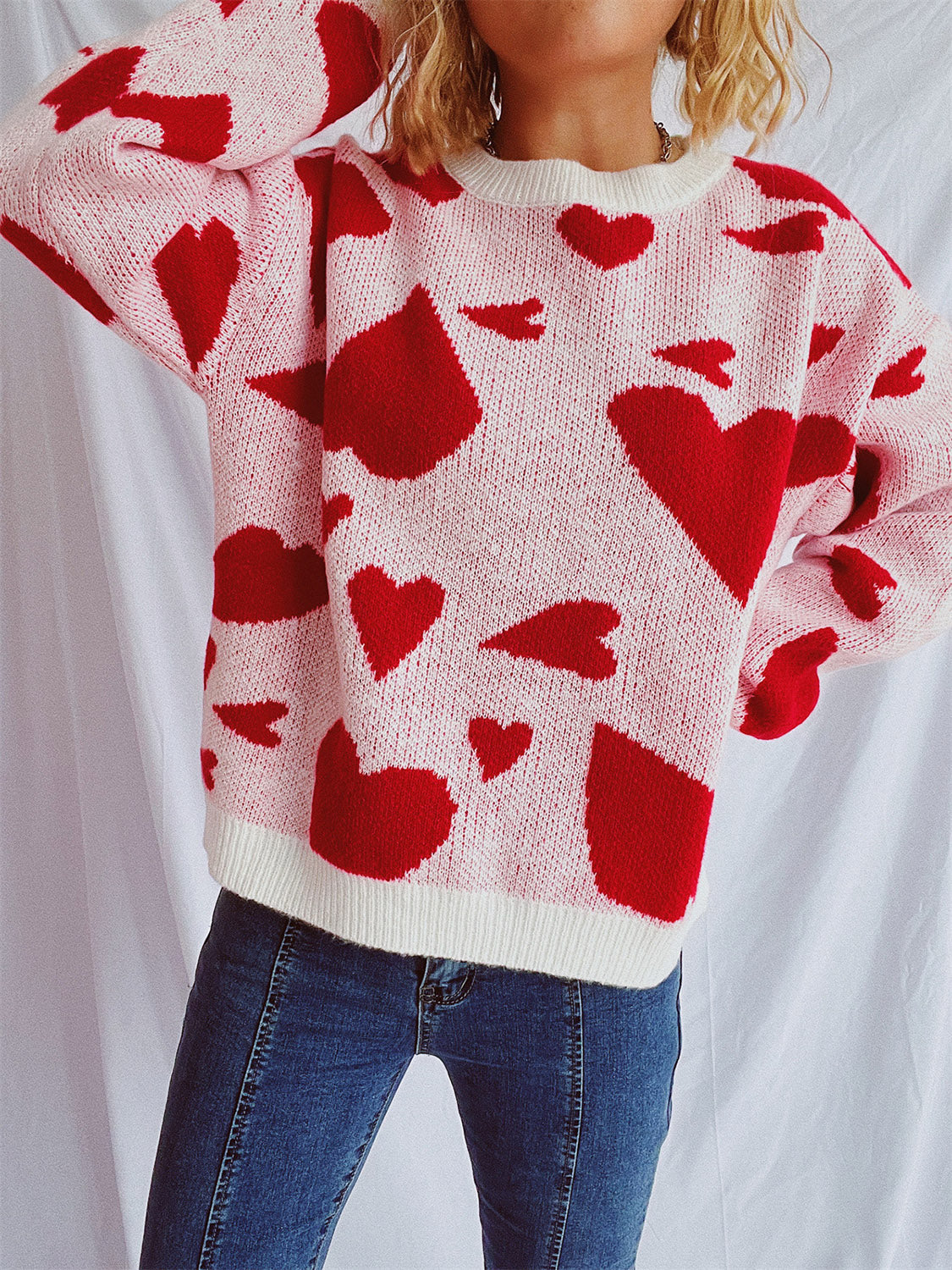 Pink acrylic knit sweater with red heart pattern and white trim.