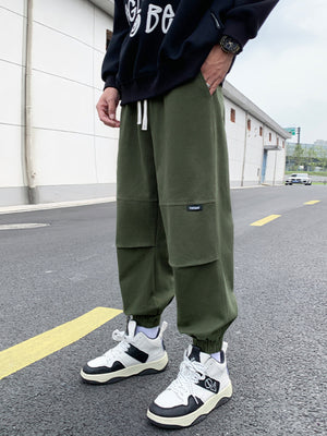 Men's army green relaxed fit joggers with drawstring and patch detail.