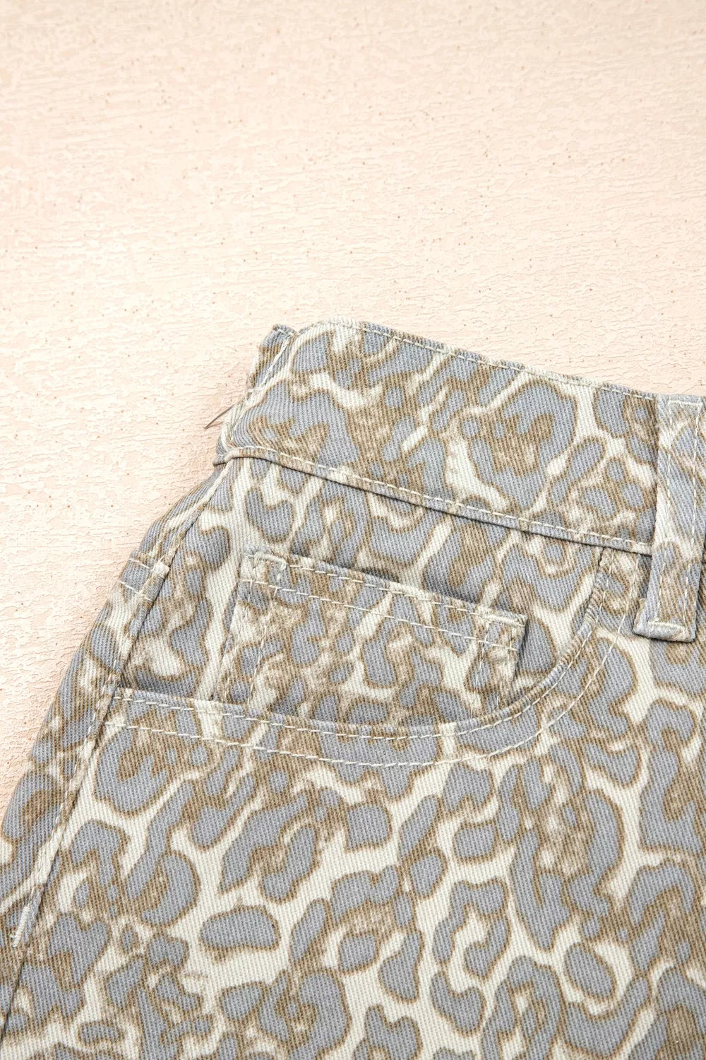 Denim shorts with a grey and tan leopard print, featuring front pockets and contrast stitching.