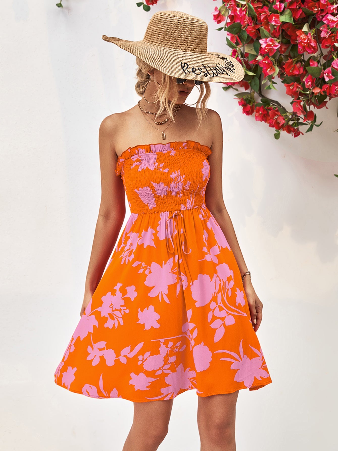 Orange smocked bandeau floral mini dress with drawstring waist and A-line skirt.